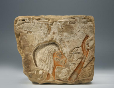Kalksteinblock mit eingetieftem Relief, dass den Kopf und die erhobene Hand der Königin Nofretete zeigt